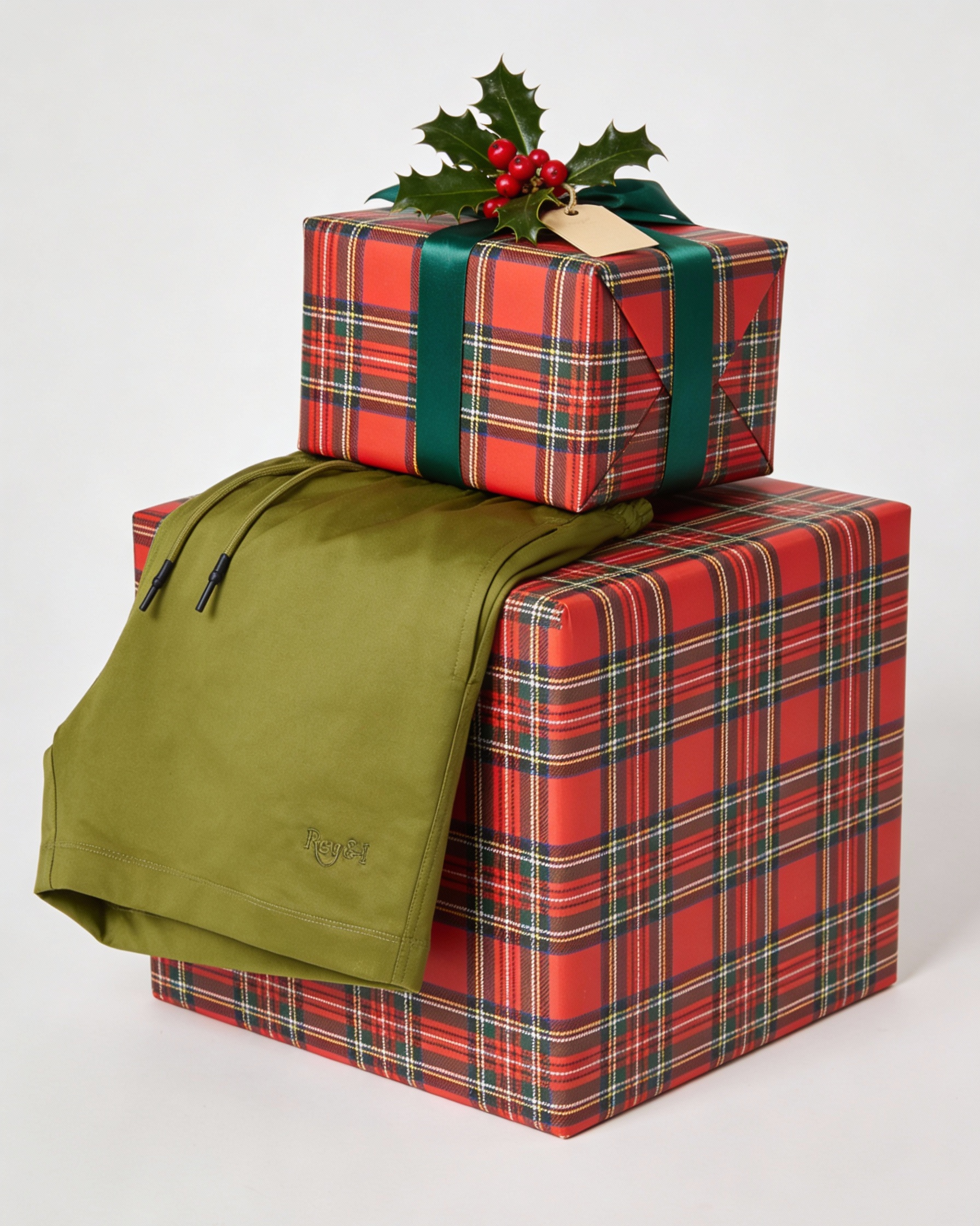 Stack of red plaid gift boxes with a green bag on a white background
